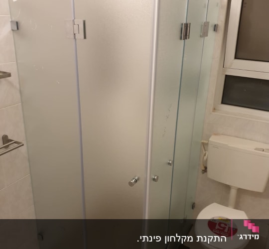 מקלחון זכוכית עם דלתות מתכת בחדר אמבטיה